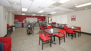 A clean, well-lit cafeteria with red and black furniture, a service counter, and a clock on the wall. - Americas Best Value Inn Pilot Mountain (Pilot Mountain)