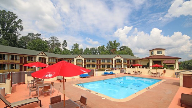 A hotel with a swimming pool, outdoor seating, and red umbrellas. - Americas Best Value Inn Pilot Mountain (Pilot Mountain)