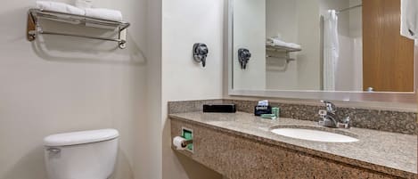 A bathroom with a toilet, sink, mirror, towel rack, and a small shelf with toiletries.