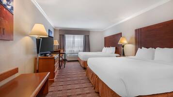 Habitación de hotel con dos camas, un escritorio con televisor y una ventana con cortinas.