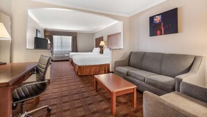 A hotel room with a bed, two bedside tables, a sofa, a desk with a chair, and a TV. - Best Western Club House Inn & Suites (Mineral Wells)