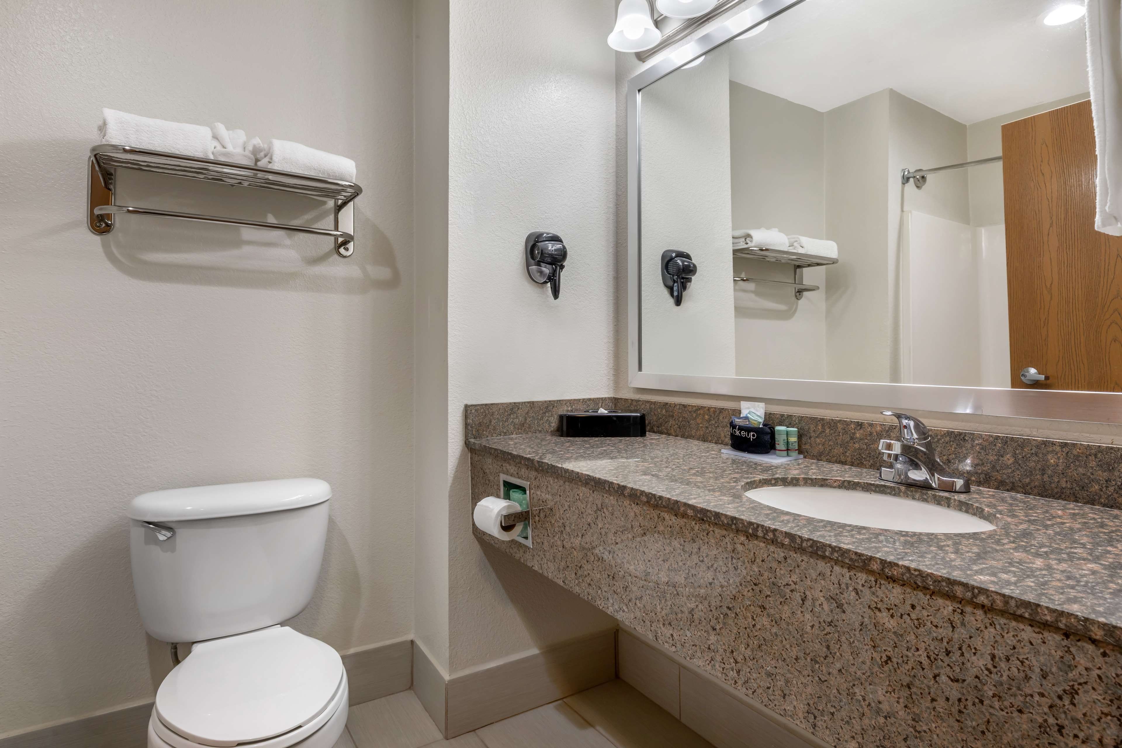Une salle de bain équipée de toilettes, d’un lavabo, d’un porte-serviettes et d’un miroir.