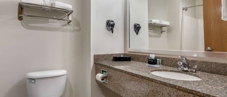 Une salle de bain équipée de toilettes, d’un lavabo, d’un porte-serviettes et d’un miroir.