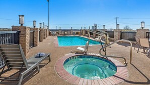 A rooftop pool area with a hot tub, lounge chairs, and a view of the city skyline. - Best Western Club House Inn & Suites (Mineral Wells)