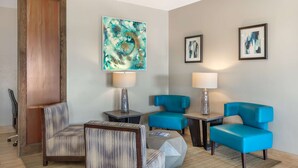 A hotel room with a wooden door, a sofa, two armchairs, a small table, and two lamps. - Best Western Club House Inn & Suites (Mineral Wells)