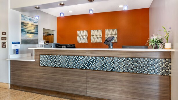 A reception desk with a modern design, a mosaic tile accent, and a digital kiosk. - Best Western Club House Inn & Suites (Mineral Wells)