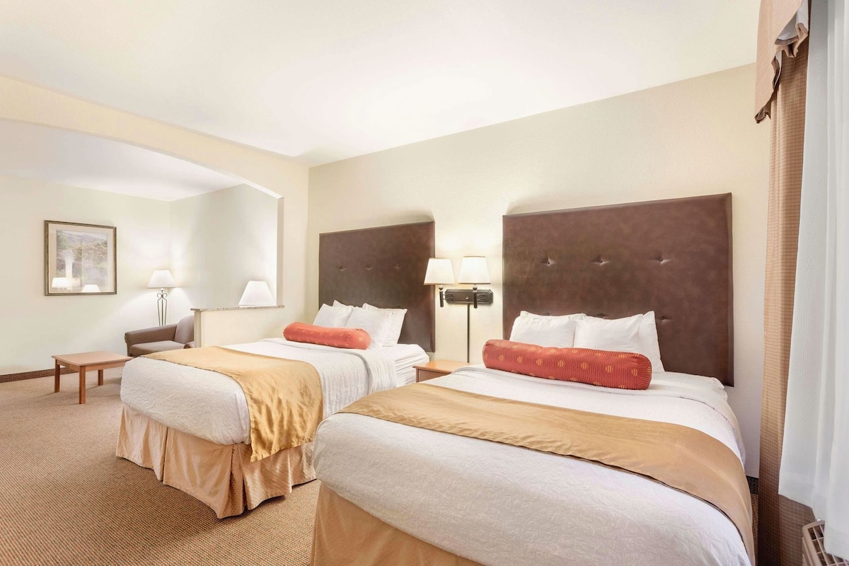 Een hotelkamer met twee bedden, een bureau en een stoel.