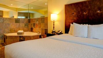 A hotel room with a large bed, a bathroom with a bathtub, and a mirror.