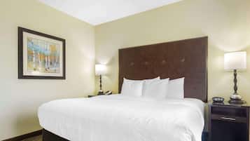 Una habitación de hotel con una cama grande, dos mesitas de noche con lámparas, un cuadro enmarcado en la pared y suelo alfombrado.