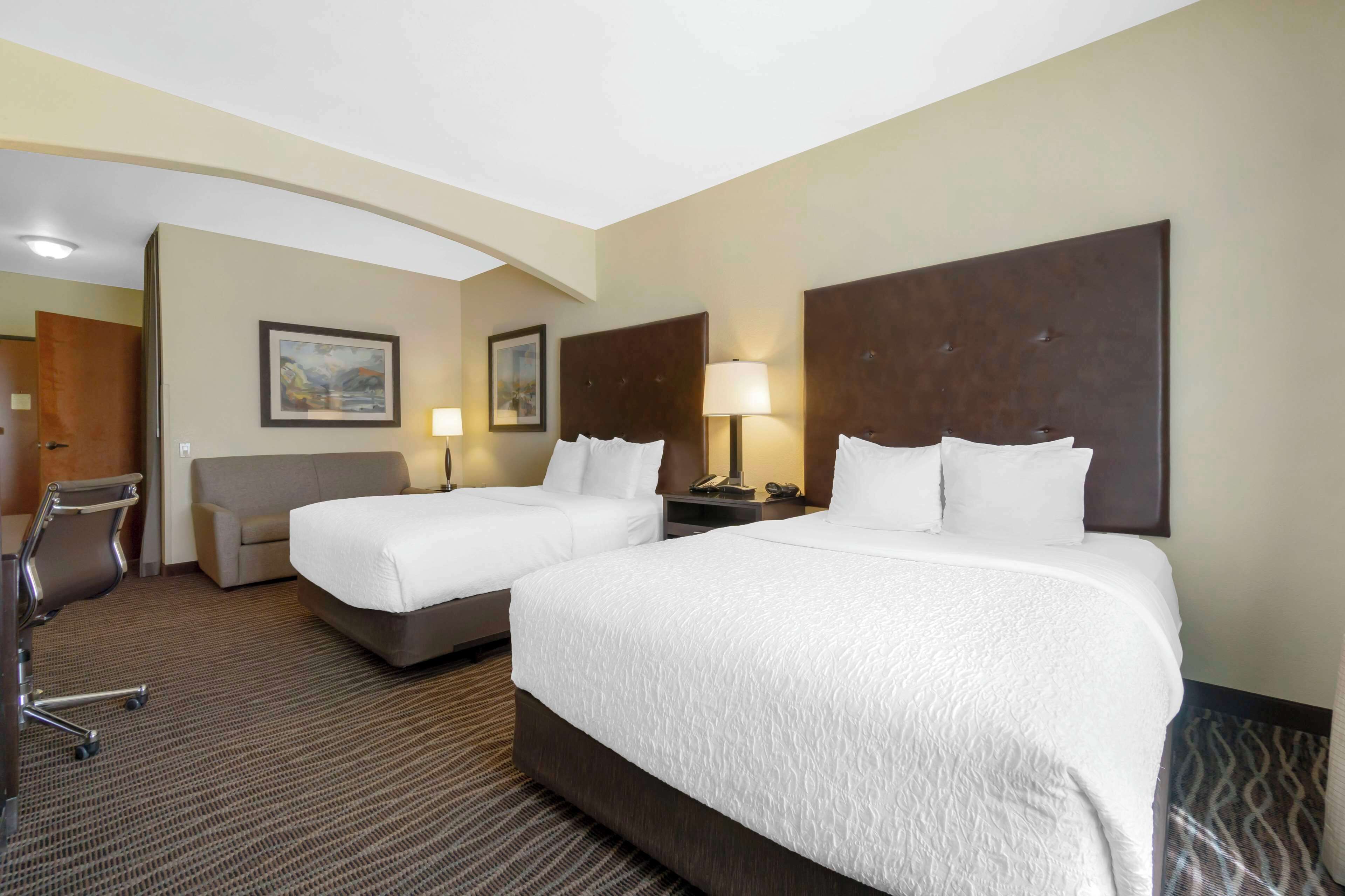 Habitación de hotel con dos camas, un escritorio y una silla.
