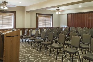 A conference room with rows of chairs, a podium, and ceiling fans.