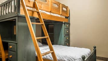 Cozy retreat with a bunk bed featuring a ladder for easy access, a desk, and ample storage.