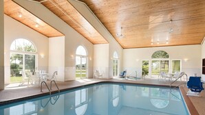 A swimming pool with a wooden ceiling, large windows, and outdoor seating. - Country Inn & Suites by Radisson, Mason City, IA (Mason City)