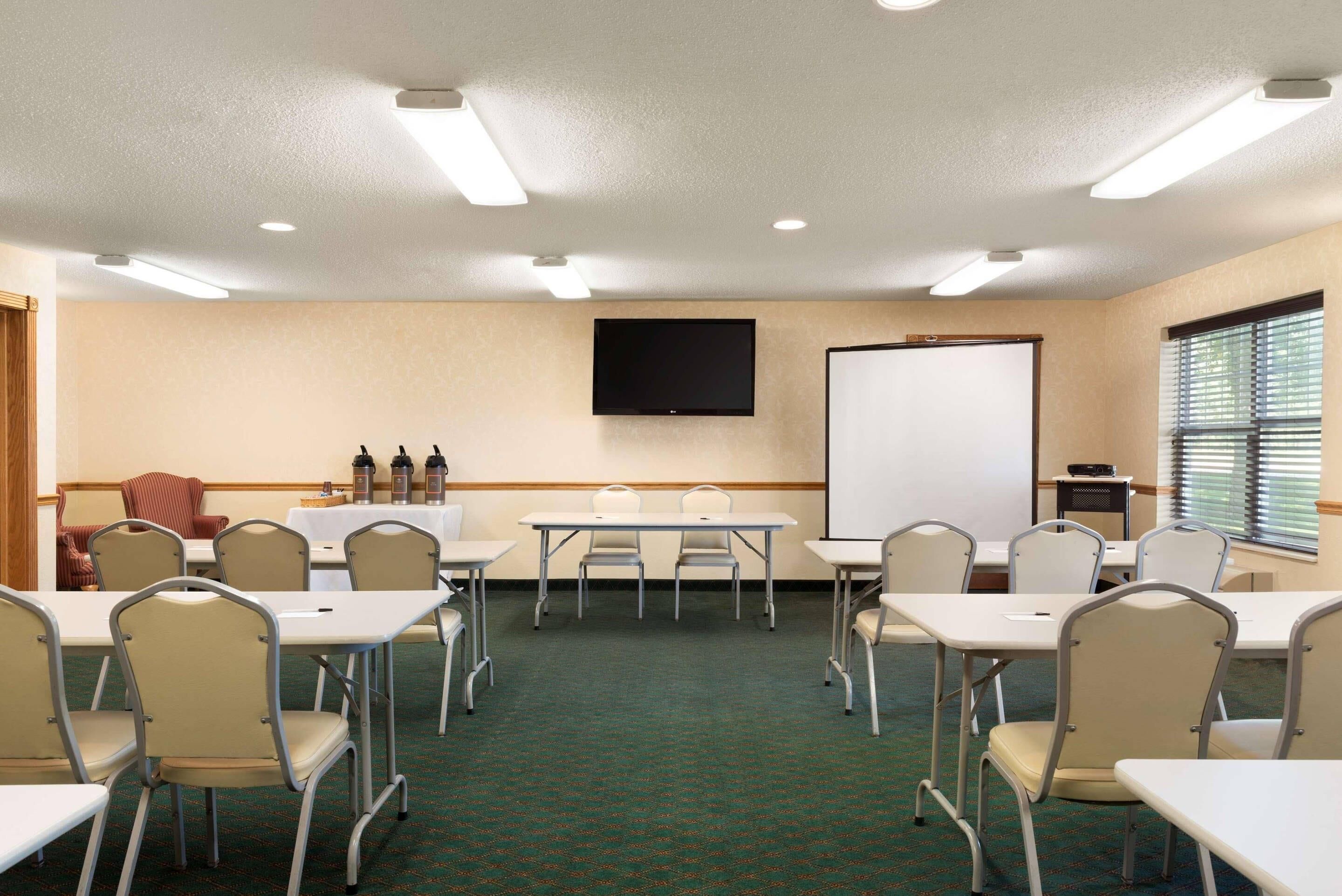 Une salle de conférence équipée d’un tableau blanc, d’un téléviseur et d’un projecteur.