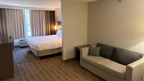 A hotel room with a bed, a sofa, a desk, and a window with curtains. - Country Inn & Suites by Radisson, Mason City, IA (Mason City)