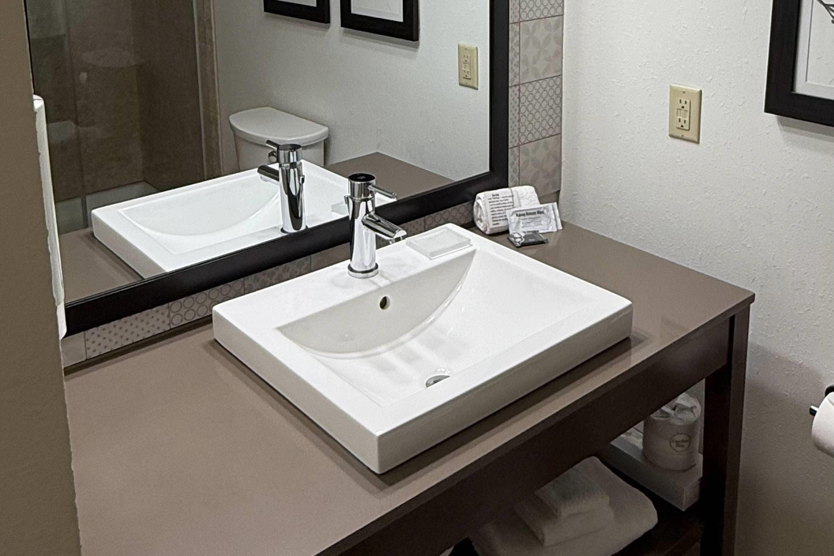Une salle de bain moderne avec un grand lavabo blanc, un miroir et des toilettes.