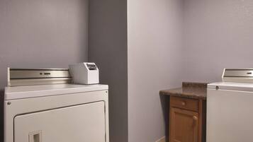 A laundry room with a washing machine, dryer, and a small cabinet.