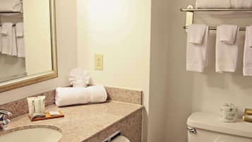 A bathroom with a granite countertop, a sink, a mirror, a towel rack, and a toilet.
