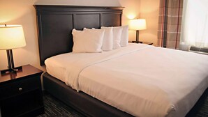 A hotel room with a large bed, dark headboard, two bedside tables with lamps, and a window with curtains. - Country Inn & Suites by Radisson, Frackville (Pottsville), PA (Pottsville)