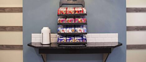 A self-serve coffee station with a coffee dispenser and a stack of coffee pods.