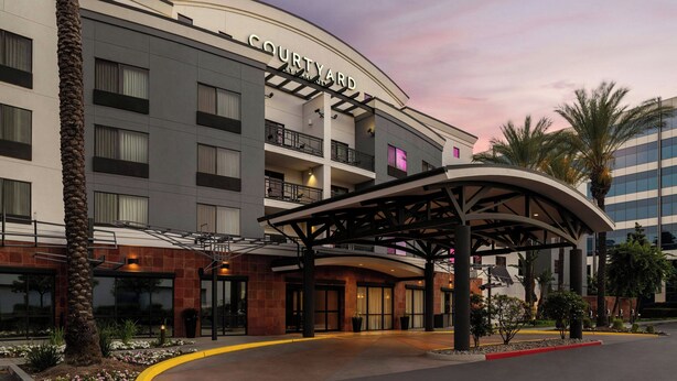 A Courtyard hotel with a modern architectural design, featuring a curved entrance canopy and multiple balconies.