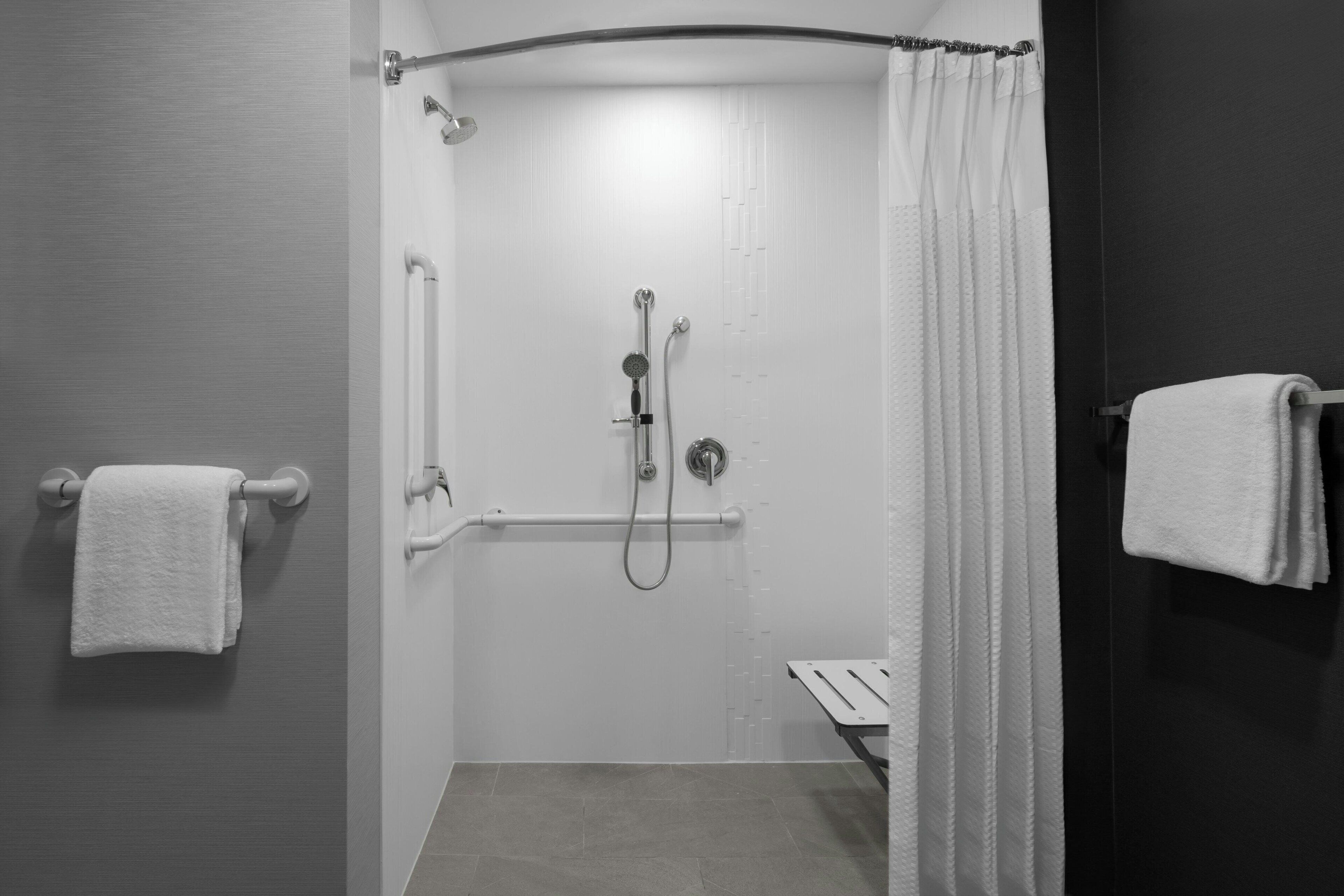 A modern shower area with a handheld showerhead, a handheld shower attachment, and a towel rack.