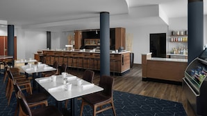A modern restaurant with a bar area, wooden tables, and chairs.