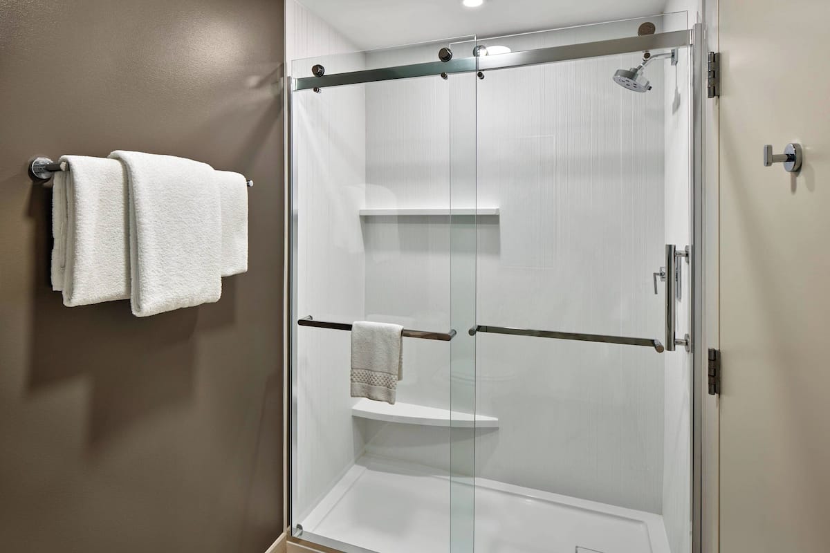 A glass-enclosed shower with a white towel on the wall.