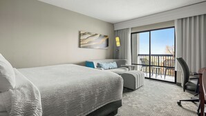 A hotel room with a large bed, a desk, a chair, a balcony with outdoor seating, and a painting on the wall. - Courtyard by Marriott Philadelphia Langhorne (Langhorne)