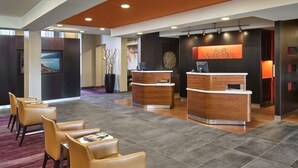 A modern reception area with two reception desks, leather chairs, and a large potted plant. - Courtyard by Marriott Philadelphia Langhorne (Langhorne)