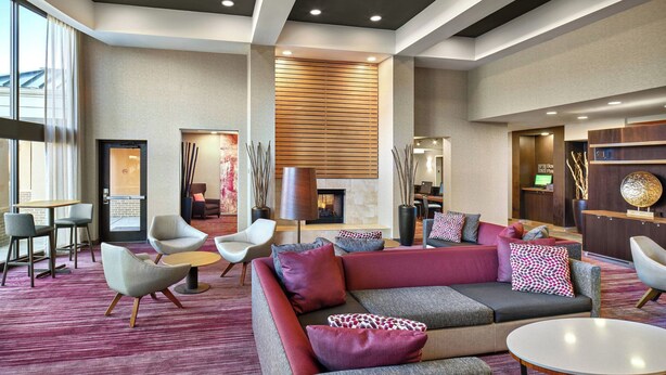 A modern lobby with a red sofa, grey armchairs, and a fireplace. - Courtyard by Marriott Philadelphia Langhorne (Langhorne)