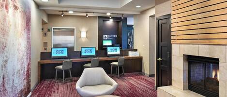 A lobby with a reception desk, computers, seating area, and a fireplace.