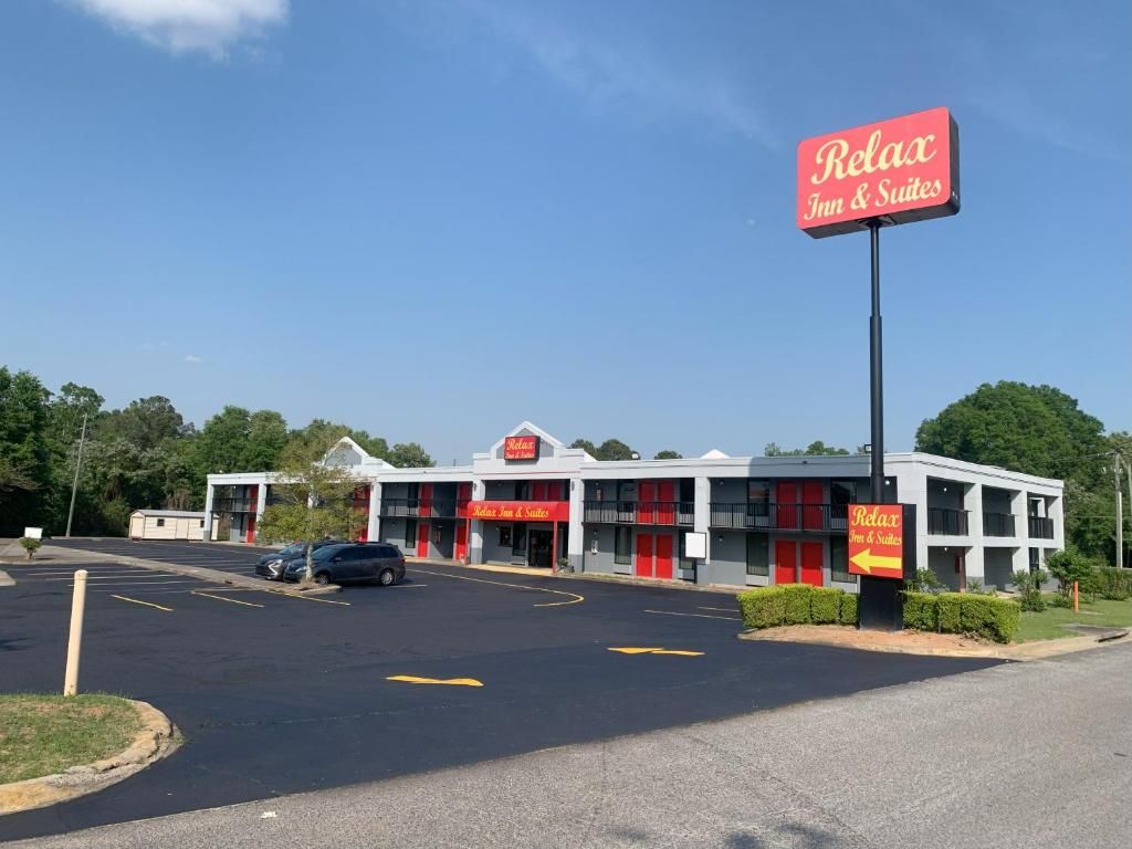 A hotel with a red and white facade, multiple entry points, and a parking lot.