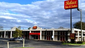 A motel with a red and white facade, multiple rooms, and a parking lot. - Relax Inn & Suites (Dublin)