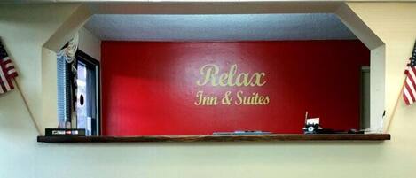 Pared roja con el texto "Relax Inn & Suites" y dos banderas estadounidenses a cada lado.