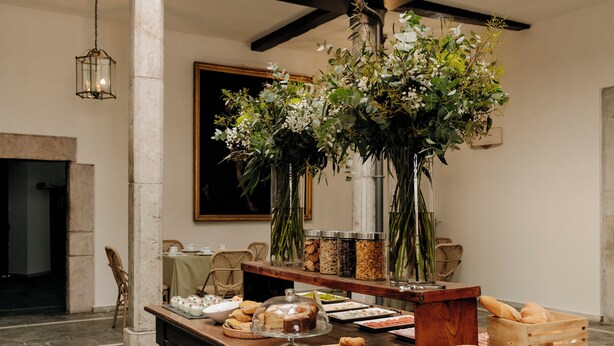 A buffet setup with various food items, a floral centerpiece, and a rustic wooden table. - Hotel PAX Casona del Busto (Pravia)