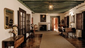 A room with wooden floors, a fireplace, and a large mirror on the wall. - Hotel PAX Casona del Busto (Pravia)
