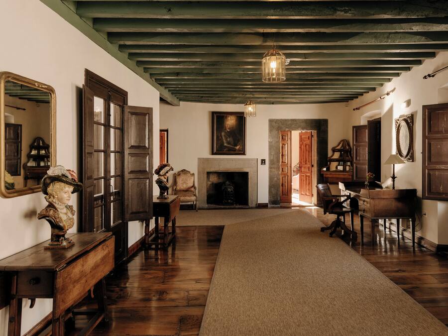 A room with wooden floors, a fireplace, and a large mirror on the wall.