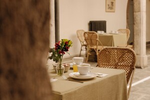 A dining table set with a vase of flowers, a glass of orange juice, and a cup of coffee.
