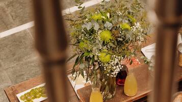 Une table ornée d’un arrangement floral, d’une assiette de fruits coupés et de plusieurs petits pots de nourriture.