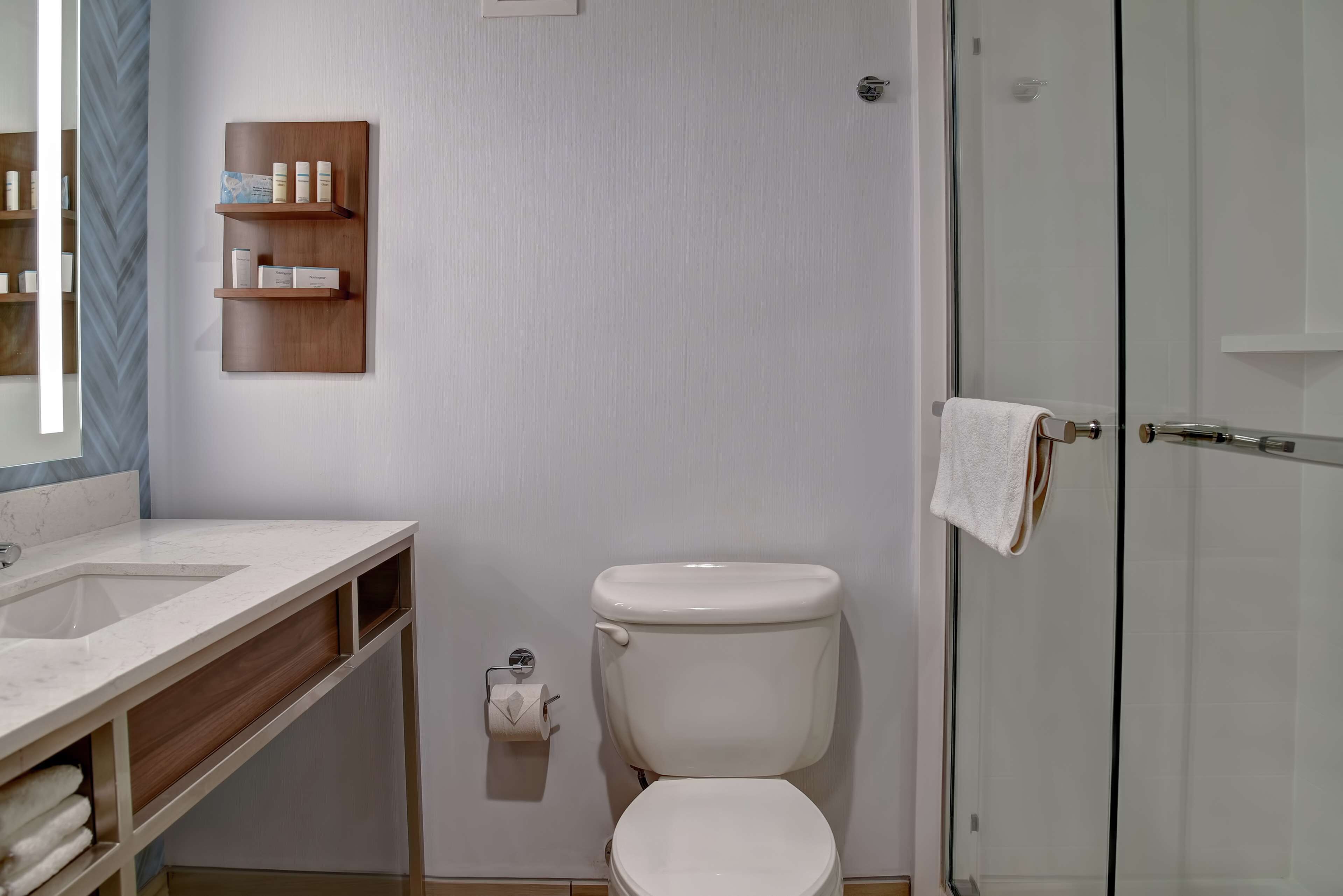 A modern bathroom with a white sink, toilet, and glass shower enclosure.