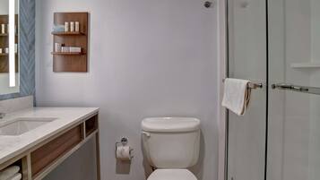 A modern bathroom with a white sink, toilet, and glass shower enclosure.