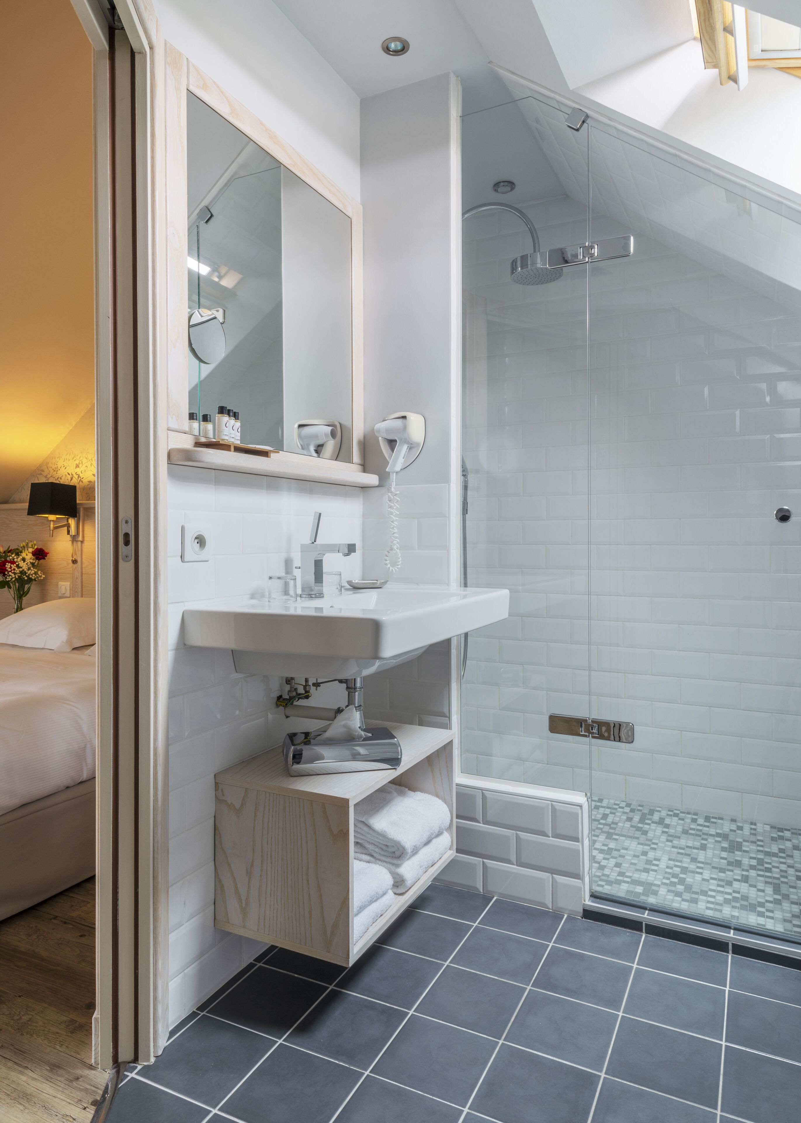 A modern bathroom with a glass shower enclosure, a white sink, and a vanity with a mirror.