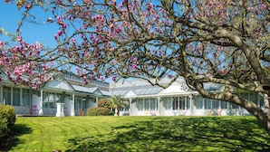 A conservatory-style building with a glass roof, surrounded by a well-maintained lawn and flowering trees. - Domaine du Limonay, The Originals Collection (Saint-Meloir-des-Ondes)