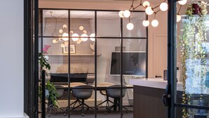 A modern office space with a glass partition, two office chairs, a desk, and a television. - Domaine du Limonay, The Originals Collection (Saint-Meloir-des-Ondes)