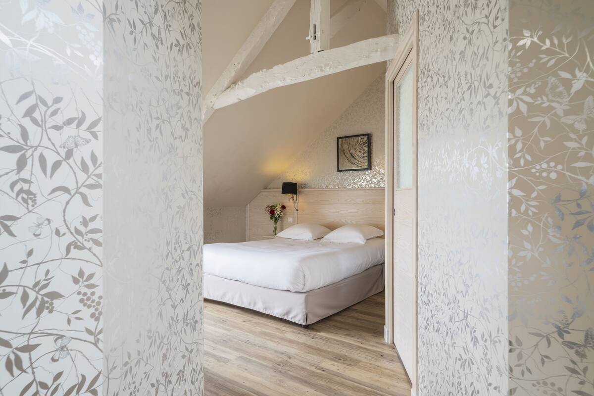 A bedroom with a bed, a nightstand, and a wall-mounted lamp.