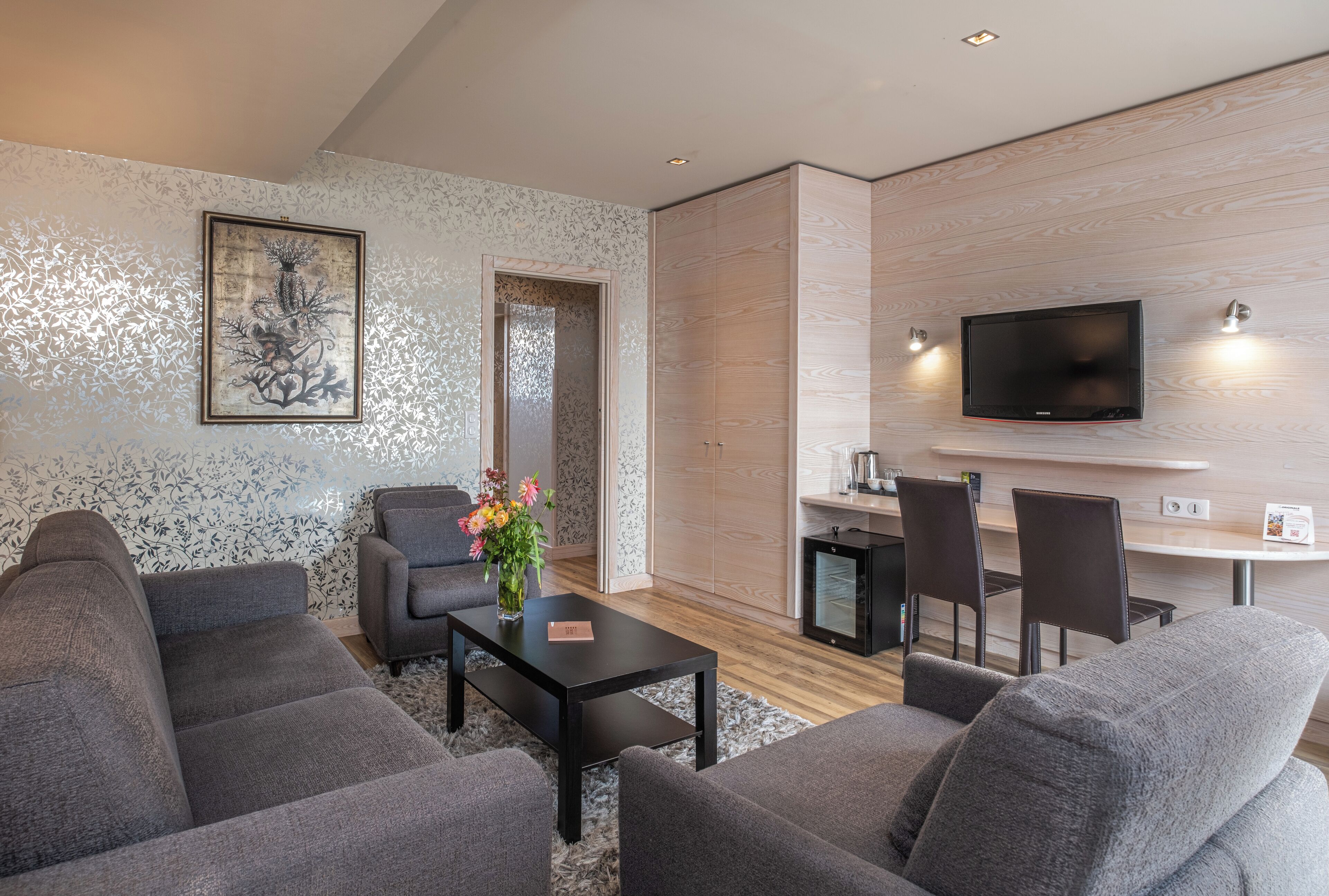 A modern living room with grey sofas, a coffee table, and a TV mounted on the wall.
