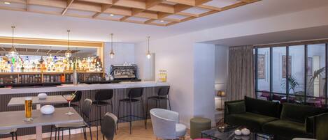 A modern bar area with a counter, seating, and a variety of bottles.