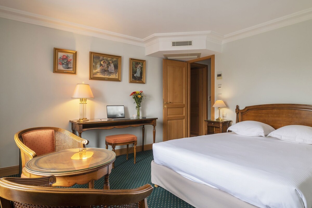 Una habitación de hotel con cama, escritorio, silla y una mesita.