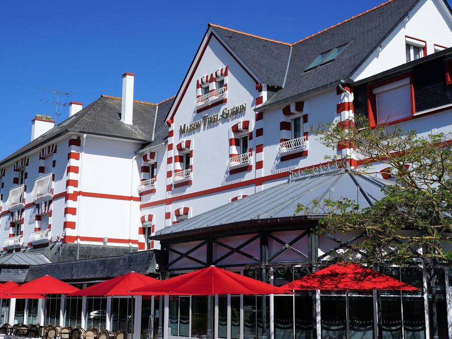 A building with a white facade and red accents, featuring balconies and a sign that reads "Mason Free Grill".